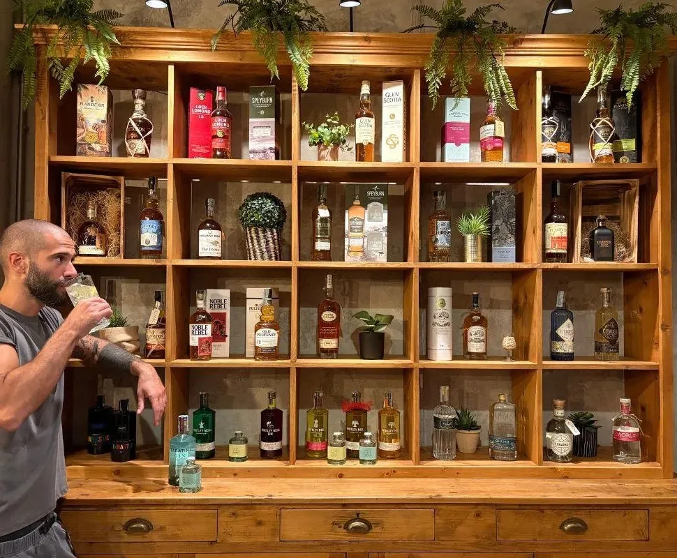 Lo scaffale in legno dei distillati, con bottiglie e piante