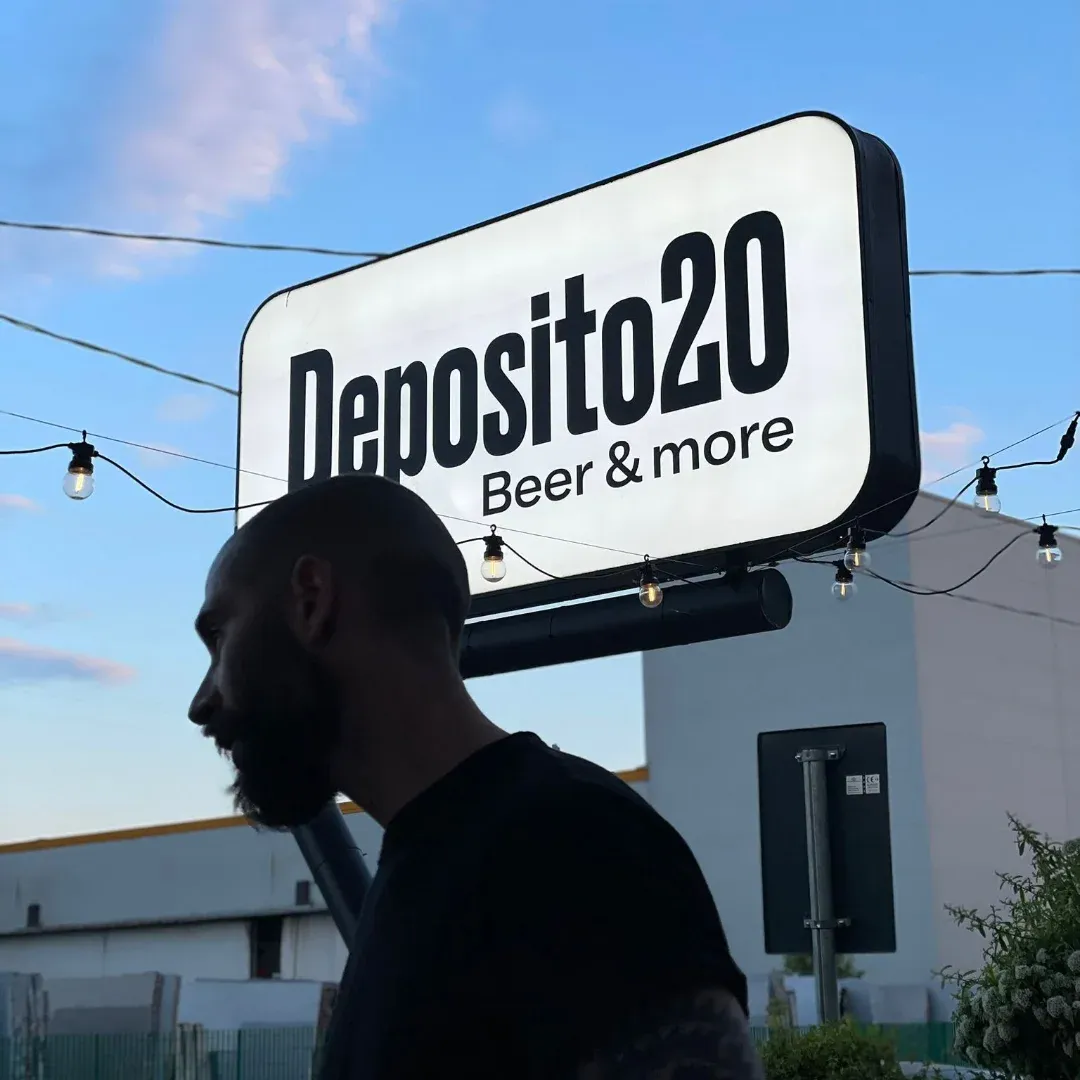 L’insegna luminosa Deposito20 — Beer & more contro il cielo della sera